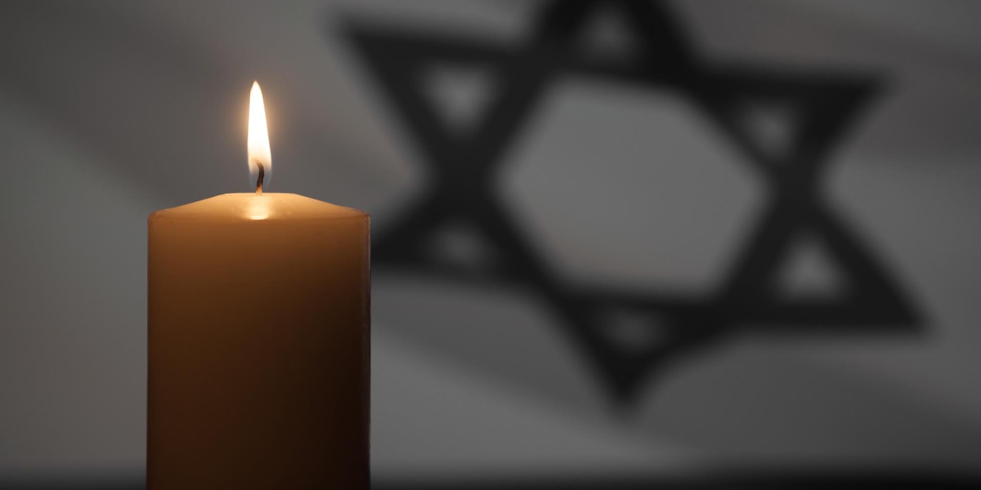 נר זיכרון דולק כשמאחוריו דגל ישראל